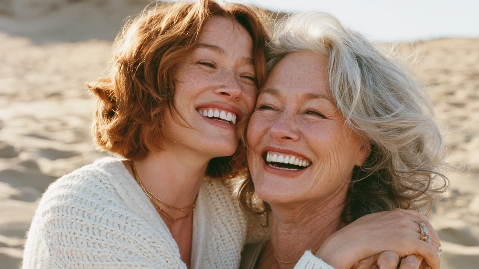 Two women in their forties and fifties laughing and raising small glasses of berry-red collagen drink