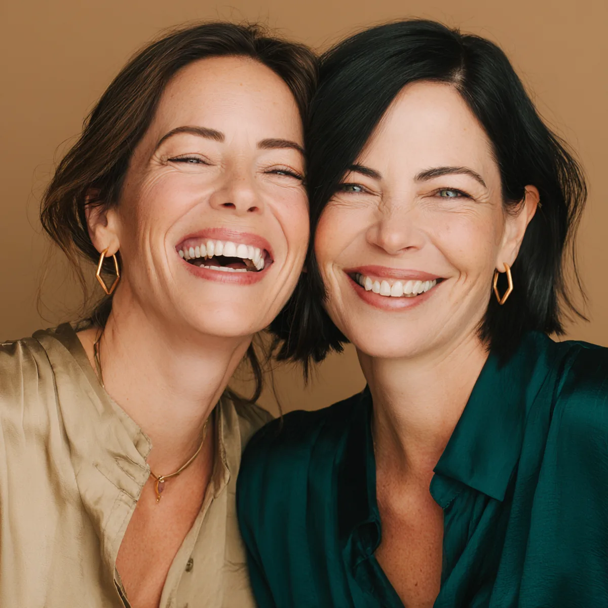 Two friends laughing cheek to cheek, soft fine lines showing at the corners of their eyes