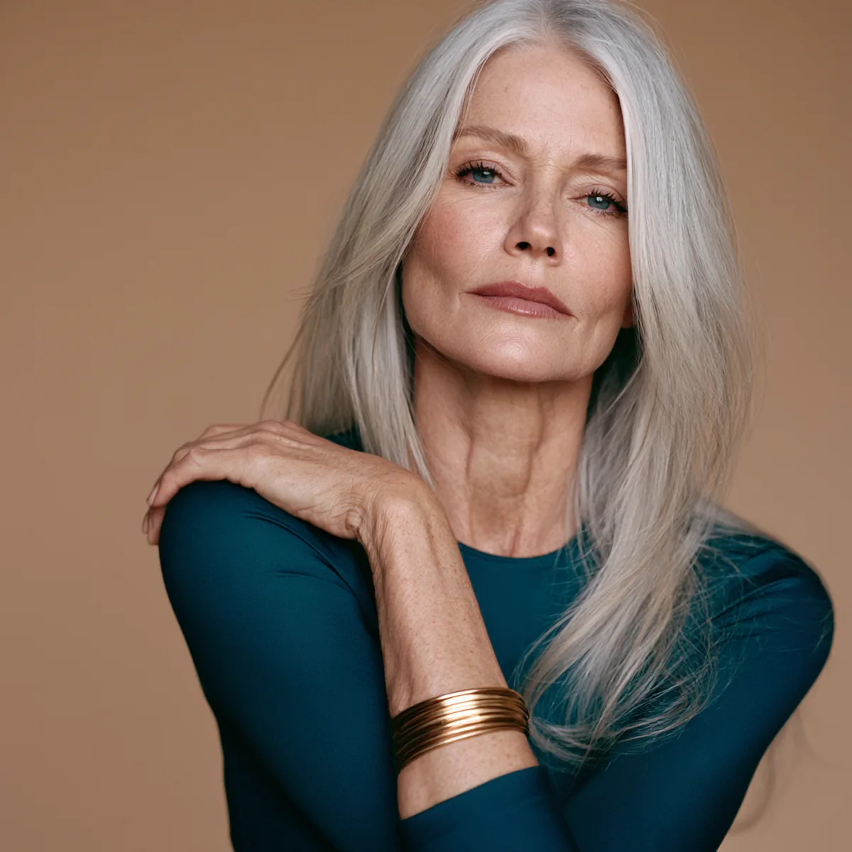 Woman in her fifties with long silver hair laughing as she shakes a pack of liquid collagen