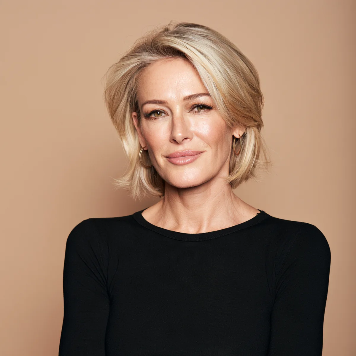 Blonde woman in her forties in a black top turning an amber glass pack in her hand with a knowing smile